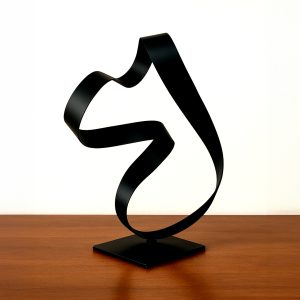 Arcus sculpture featuring a flowing black steel ribbon form on a square base, displayed on a wood surface.